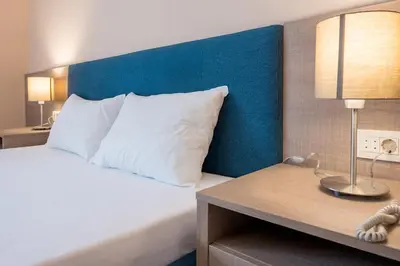 a bedroom with a bed with a blue headboard and a table at Garni Hotel MB in Budva
