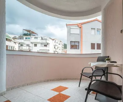 a balcony with chairs and a table and buildings at Garni Hotel MB in Budva