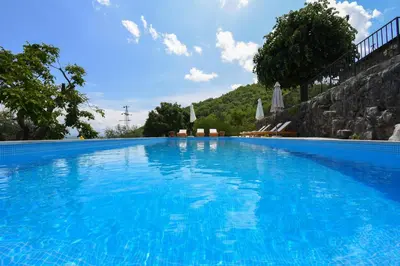 a large blue swimming pool with chairs and umbrellas at GRANDFATHER'S Secret in Danilovgrad
