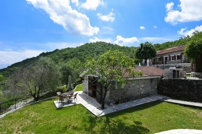 a garden with a table and a chair on a wall at GRANDFATHER'S Secret in Danilovgrad