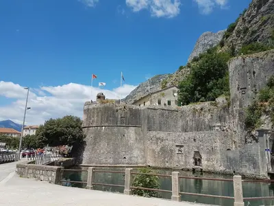 a large stone wall next to a body of water at S&I room in Kotor