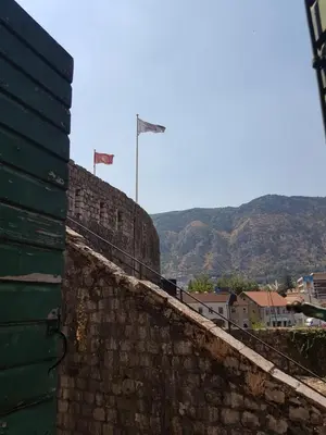 a stone wall with two flags on top of it at S&I room in Kotor