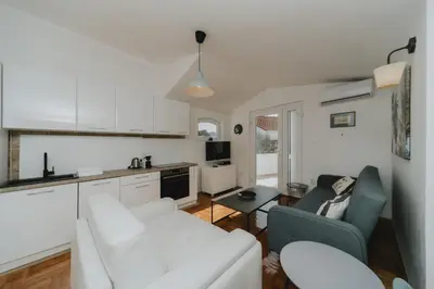 a living room with a white couch and a kitchen at Panoramic Apartment in Budva