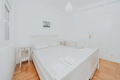 a white bedroom with a large bed and a table at Panoramic Apartment in Budva