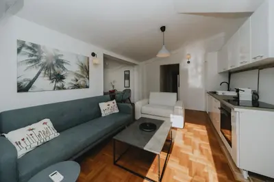 a living room with a green couch and a kitchen at Panoramic Apartment in Budva