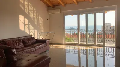 a living room with a couch and a balcony at De Luxe Apartment with a Seaview in Petrovac na Moru