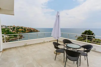 a balcony with a table and chairs and the ocean at Teuta Apartments in Ulcinj