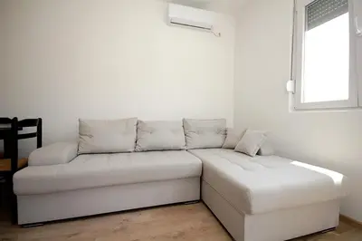 a white couch in a room with a window at Apartmani Begovic in Bar