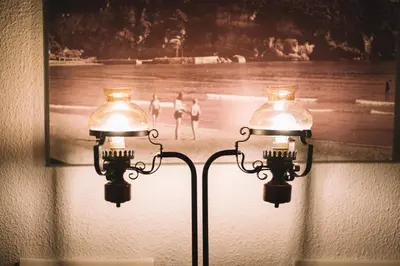 two lights on a wall with a picture of people on the beach at Kulla e Balshajve in Ulcinj