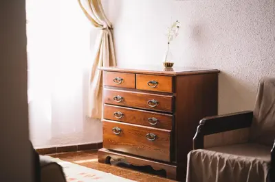 a dresser in a room with a window and a chair at Kulla e Balshajve in Ulcinj