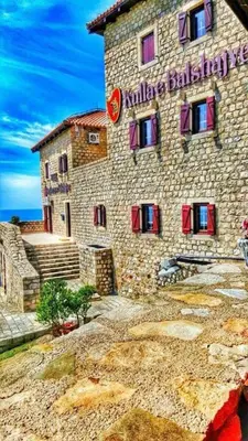 a large stone building with red windows on a hill at Kulla e Balshajve in Ulcinj