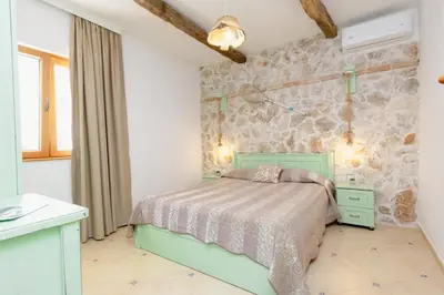 a bedroom with a green bed and a stone wall at Apartments Bazar in Ulcinj
