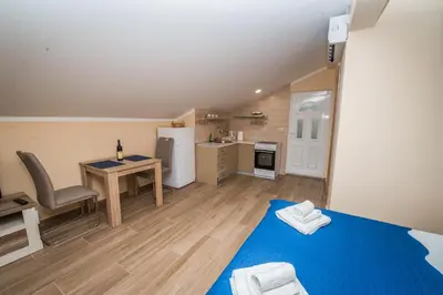 a small kitchen with a table and a blue bed in a room at Apartment Vrutak in Kotor