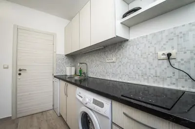 a kitchen with white cabinets and a washer and dryer at Apartment Vrutak in Kotor