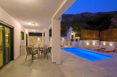 a patio with a table and chairs and a pool at Villa Latina 2 in Budva