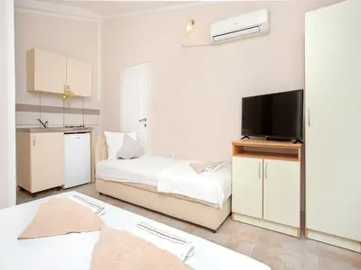 a white bedroom with a bed and a tv at Apartments MIK5 - Famous Beach Jaz in Budva