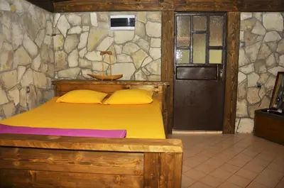 a bedroom with a wooden bed and a stone wall at Skadar Lake House Virpazar in Virpazar