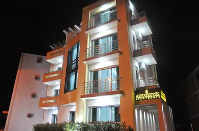 a tall orange building with balconies at night at Ambassador & Ambassador Lux Apartments in Ulcinj