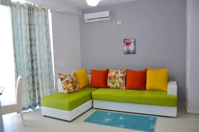 a living room with a green couch with colorful pillows at Ambassador & Ambassador Lux Apartments in Ulcinj