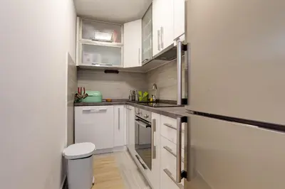a small kitchen with white cabinets and stainless steel appliances at Varja 2 Apartment in Sveti Stefan