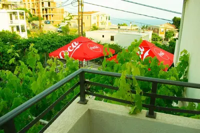 two red umbrellas on a balcony on a building at Apartments Stojanovic in Ulcinj