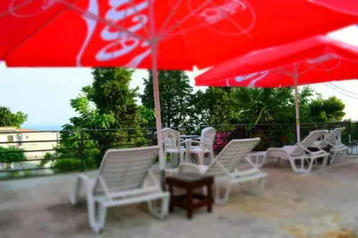 a group of chairs and tables with red umbrellas at Apartments Stojanovic in Ulcinj
