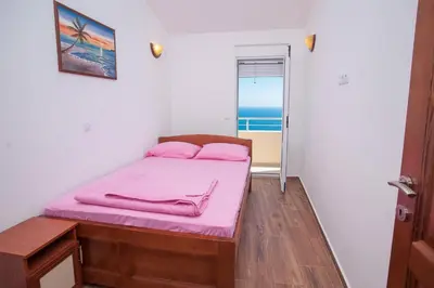 a bedroom with a bed with pink sheets and a window at Apartments Onyx in Ulcinj