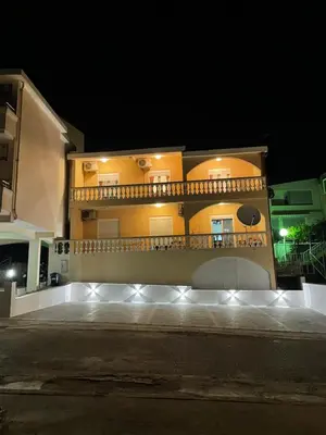 a large yellow building with a balcony at night at Apartments Onyx in Ulcinj