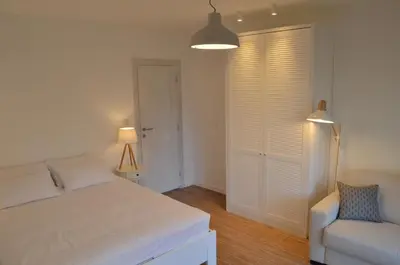 a white bedroom with a bed and a chair at Casablanca Apartments in Budva