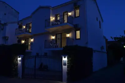 a white house with lights on the side of it at Casablanca Apartments in Budva