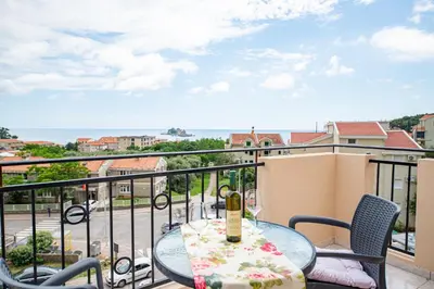 a table with a bottle of wine on a balcony at Apartments Vjera Petrovac in Petrovac na Moru