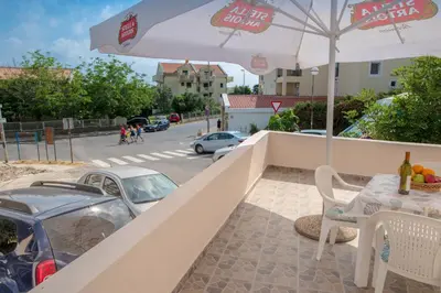 a balcony with an umbrella and a table and chairs at Apartments Vjera Petrovac in Petrovac na Moru