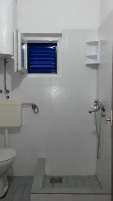 a bathroom with a shower and a toilet and a window at Apartmani Drašković in Petrovac na Moru
