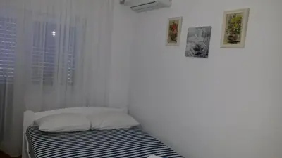 a bed in a room with three pictures on the wall at Apartmani Drašković in Petrovac na Moru