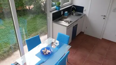 a kitchen with a blue table and chairs and a sink at Apartmani Drašković in Petrovac na Moru