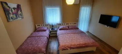 two beds in a small room with a tv at Home Šćekić in Budva