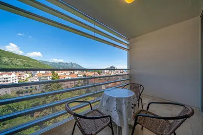 a balcony with two chairs and a table and a large window at Apt 