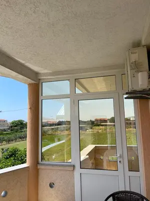 a room with two large windows and a door at Apartments Vali in Ulcinj