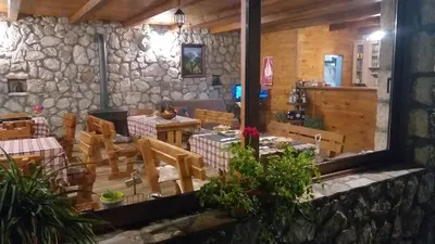 a dining room with tables and chairs and a stone wall at Village house - Novak Rijecani in Rijeka Crnojevića