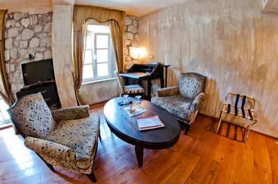 a living room with a table and chairs and a piano at Boutique Hotel Astoria in Kotor