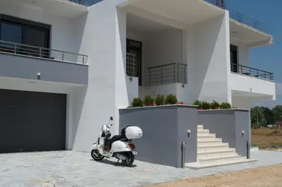 a scooter parked in front of a white house at Flo Apartments in Ulcinj