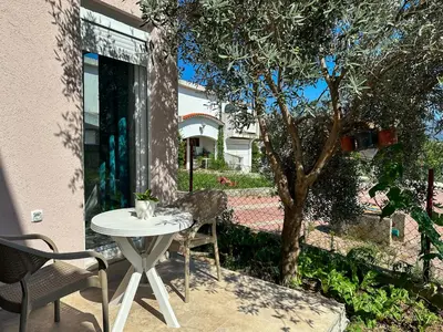 a patio with a table and chairs and a tree at Jasmin apartmani in Bar