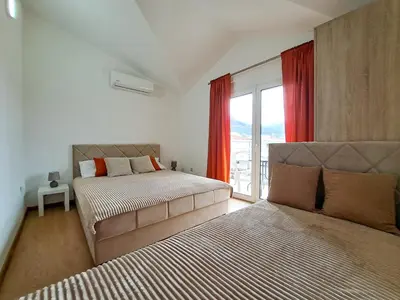 a bedroom with two beds and a window with red curtains at Jasmin apartmani in Bar