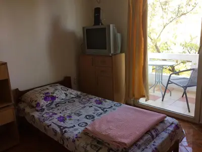 a bedroom with a bed and a tv and a balcony at Guesthouse Berlin in Bar