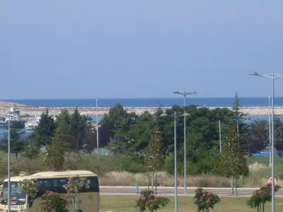 a bus driving down a road next to the ocean at Studio apartmani DENNUS in Bar