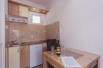 a kitchen with a table with two glasses of wine at Apartmani 