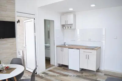 a white kitchen with a sink and a table at Apartmani 