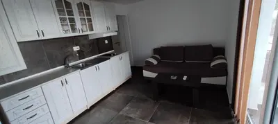 a kitchen with white cabinets and a black chair at Zoran Apartments in Sveti Stefan