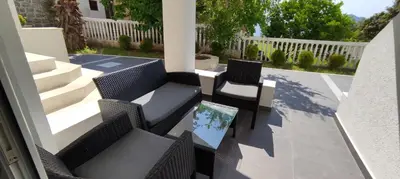 a patio with two chairs and a table with a screen at Zoran Apartments in Sveti Stefan