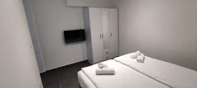 a white room with two beds and a television at Zoran Apartments in Sveti Stefan